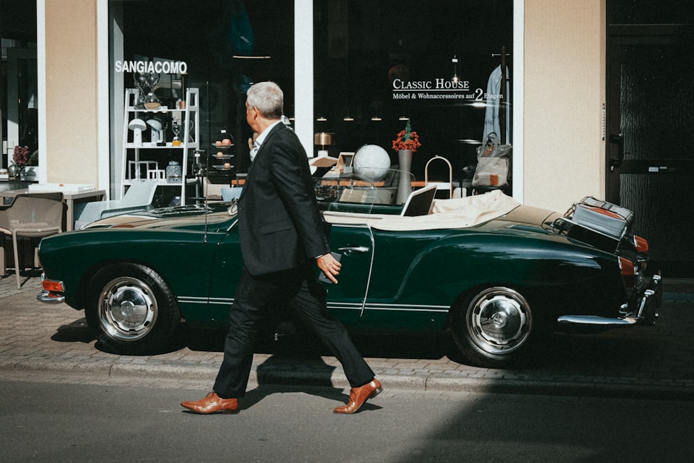 man in black suit standing beside green car