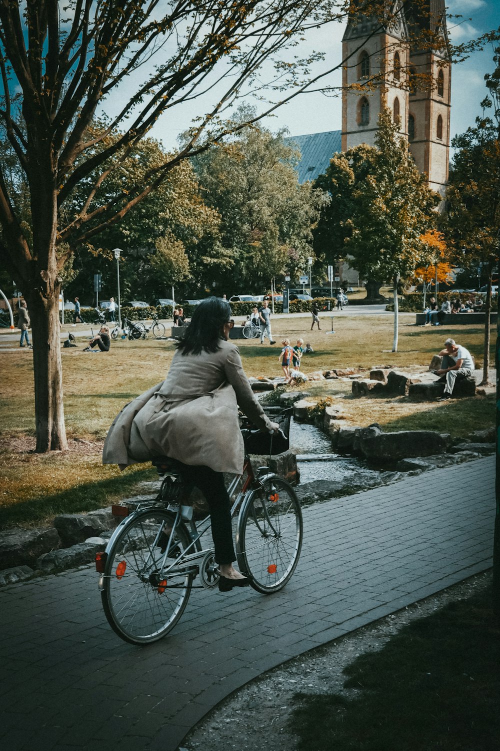 donna in giacca grigia che va in bicicletta sulla strada di cemento grigia durante il giorno