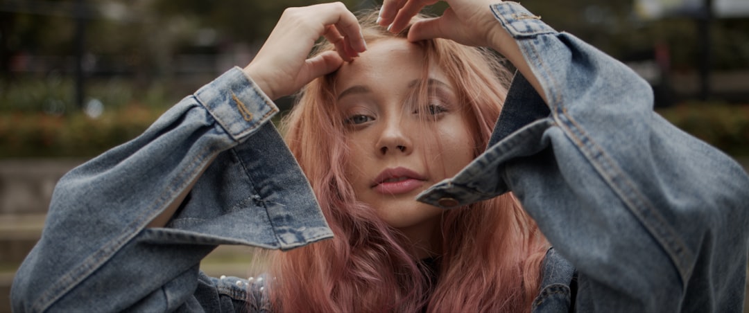 woman in blue denim jacket holding her hair