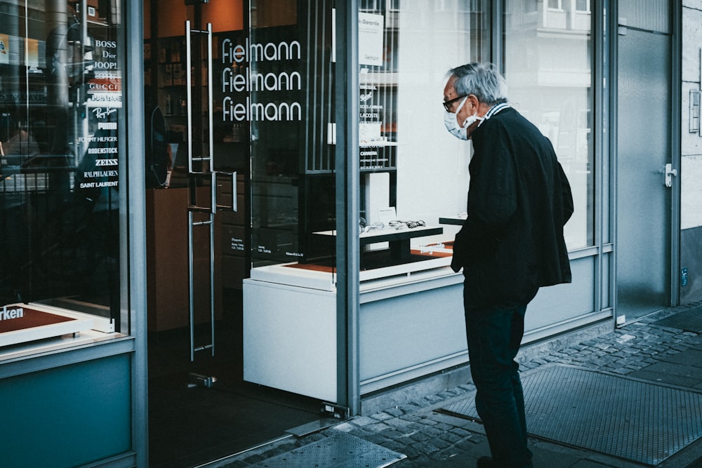 um homem em pé na frente de uma vitrine de loja