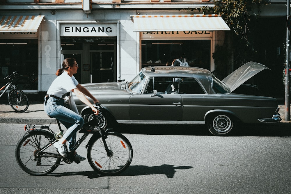 a woman riding a bike down a street next to a car