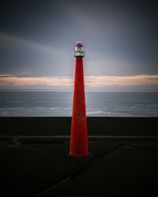 red and white lighthouse near body of water during daytime