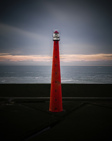 red and white lighthouse near body of water during daytime