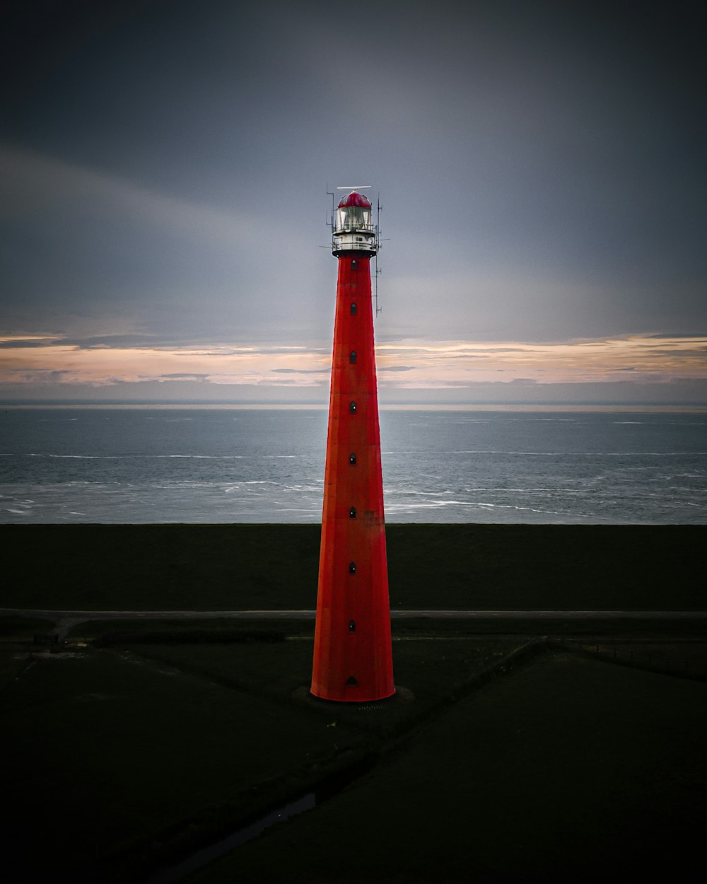 red and white lighthouse near body of water during daytime