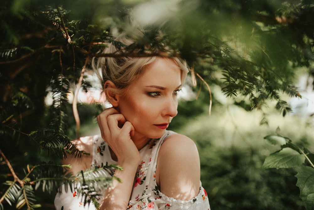 girl in white and blue tank top standing near green leaf plant during daytime