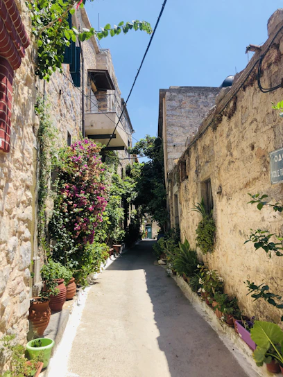 Sunlit narrow street in Gaeta’s medieval borgo with rustic stone walls and vibrant flower pots.