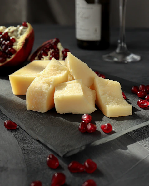 sliced cheese on black plate beside wine glass