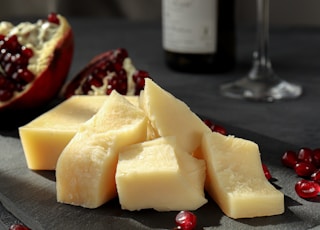 sliced cheese on black plate beside wine glass