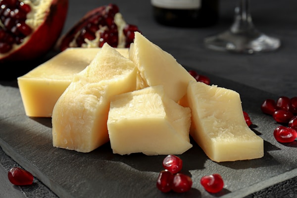 sliced cheese on black plate beside wine glass