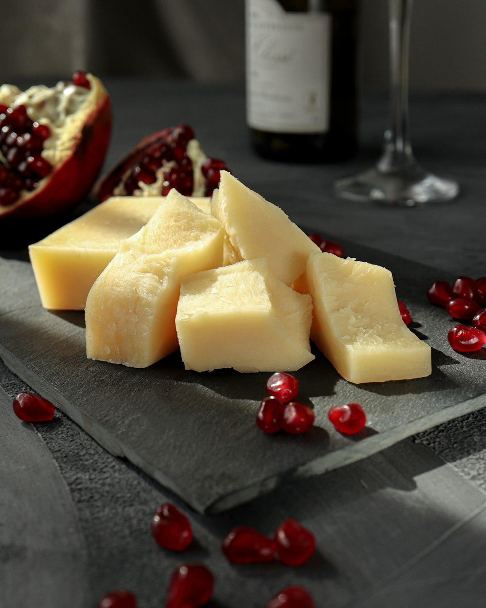 fromage tranché sur assiette noire à côté d’un verre à vin