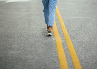 woman in blue denim jeans and brown hat walking on the street during daytime