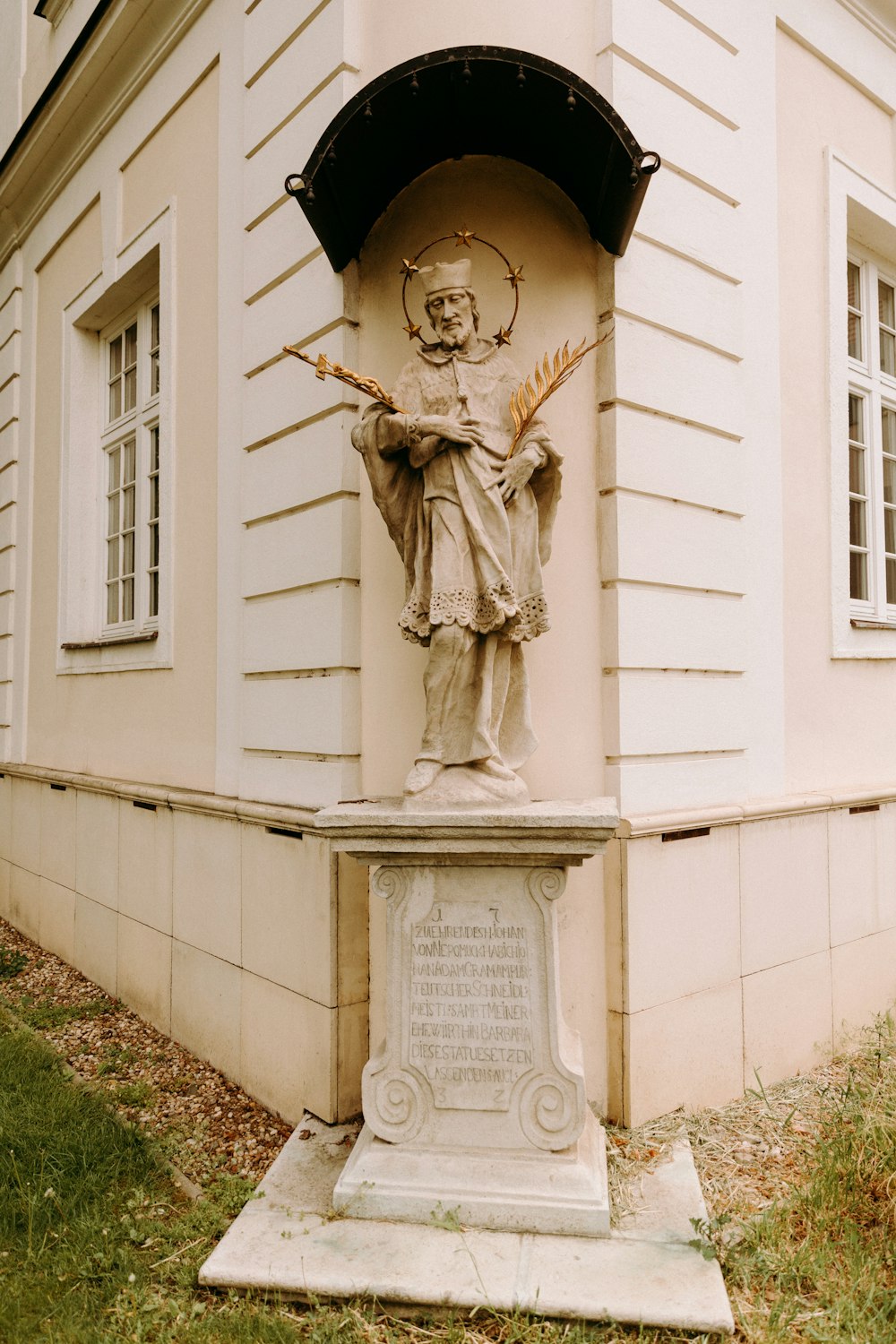 Uomo che tiene la statua del libro vicino all'edificio in cemento bianco durante il giorno