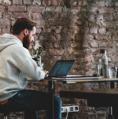 man in beige hoodie sitting on chair using laptop computer