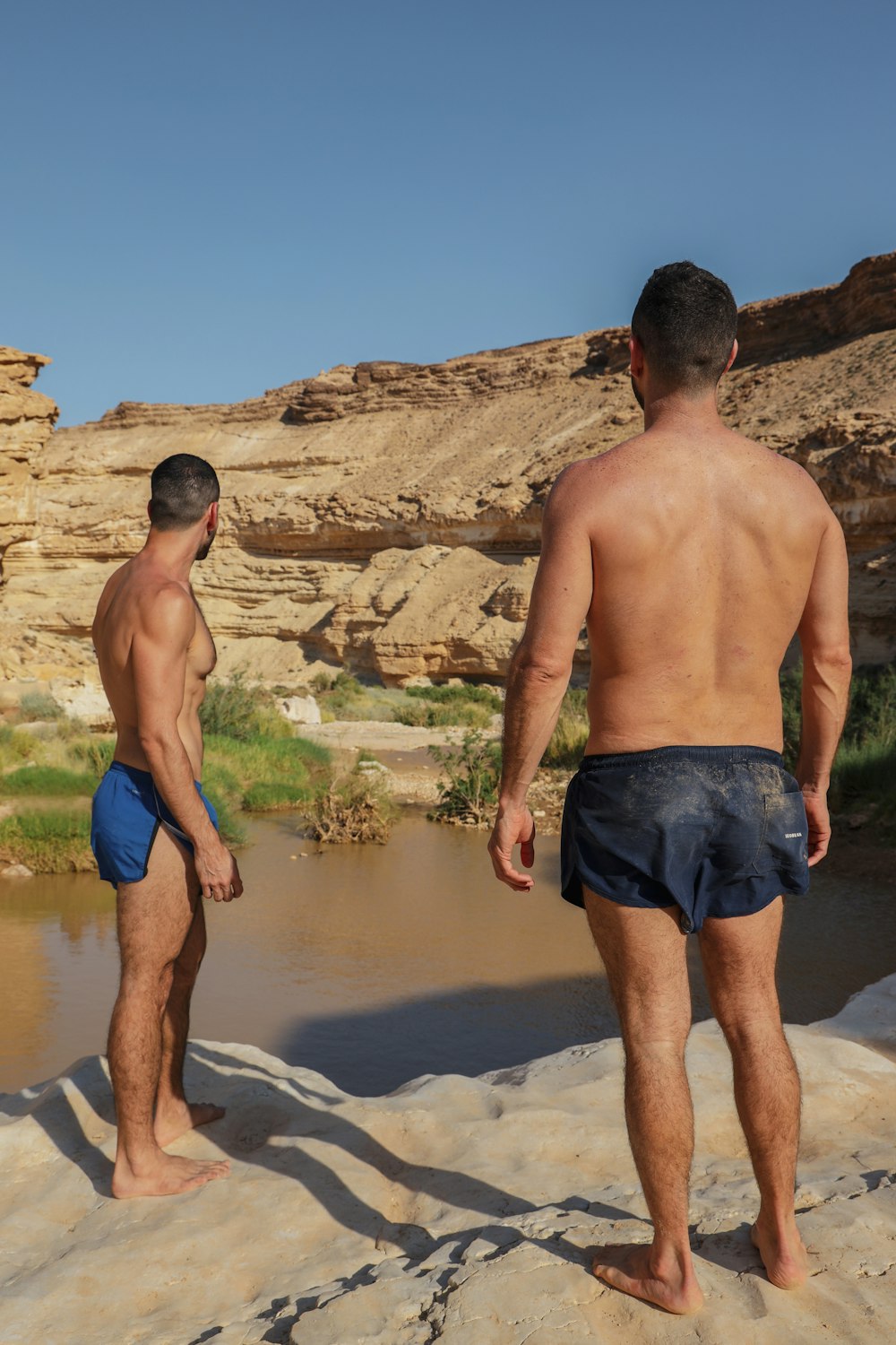 2 Männer stehen tagsüber auf Felsen in der Nähe von Gewässern