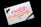 A piece of paper with colorful calligraphy reading 'Creativity is Contagious, Pass it on' written in vibrant pink and orange ink. The paper rests on a dark surface, with a black pen placed beside it. A motorcycle keychain sits on the top left corner of the paper.