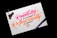 A piece of paper with colorful calligraphy reading 'Creativity is Contagious, Pass it on' written in vibrant pink and orange ink. The paper rests on a dark surface, with a black pen placed beside it. A motorcycle keychain sits on the top left corner of the paper.