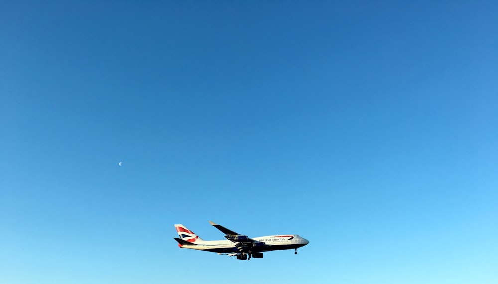 white and red airplane in mid air during daytime