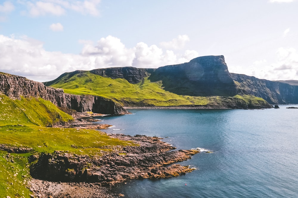 green mountain beside body of water during daytime