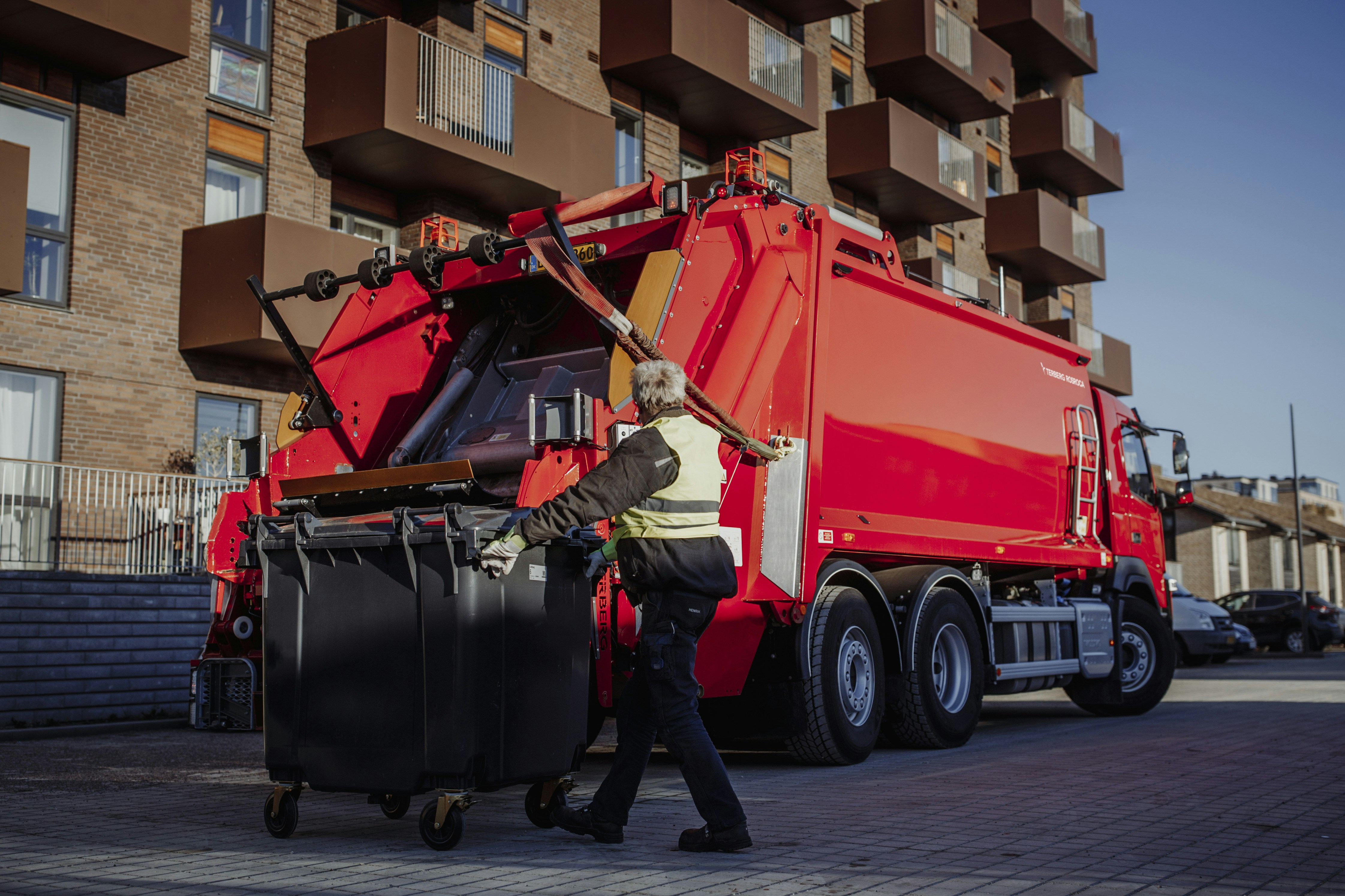 man in green jacket and black pants sitting on red truck