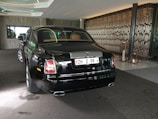 A sleek black Rolls Royce Phantom with red carpet rolled out in front of a luxury hotel