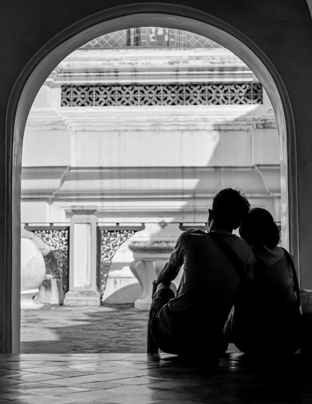 grayscale photo of man and woman sitting on chair