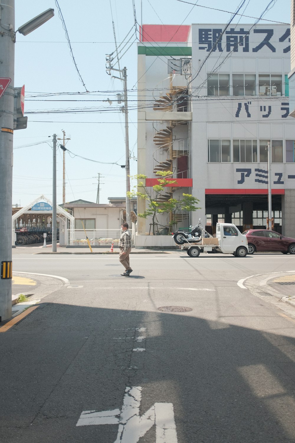 man in black jacket and black pants walking on sidewalk during daytime