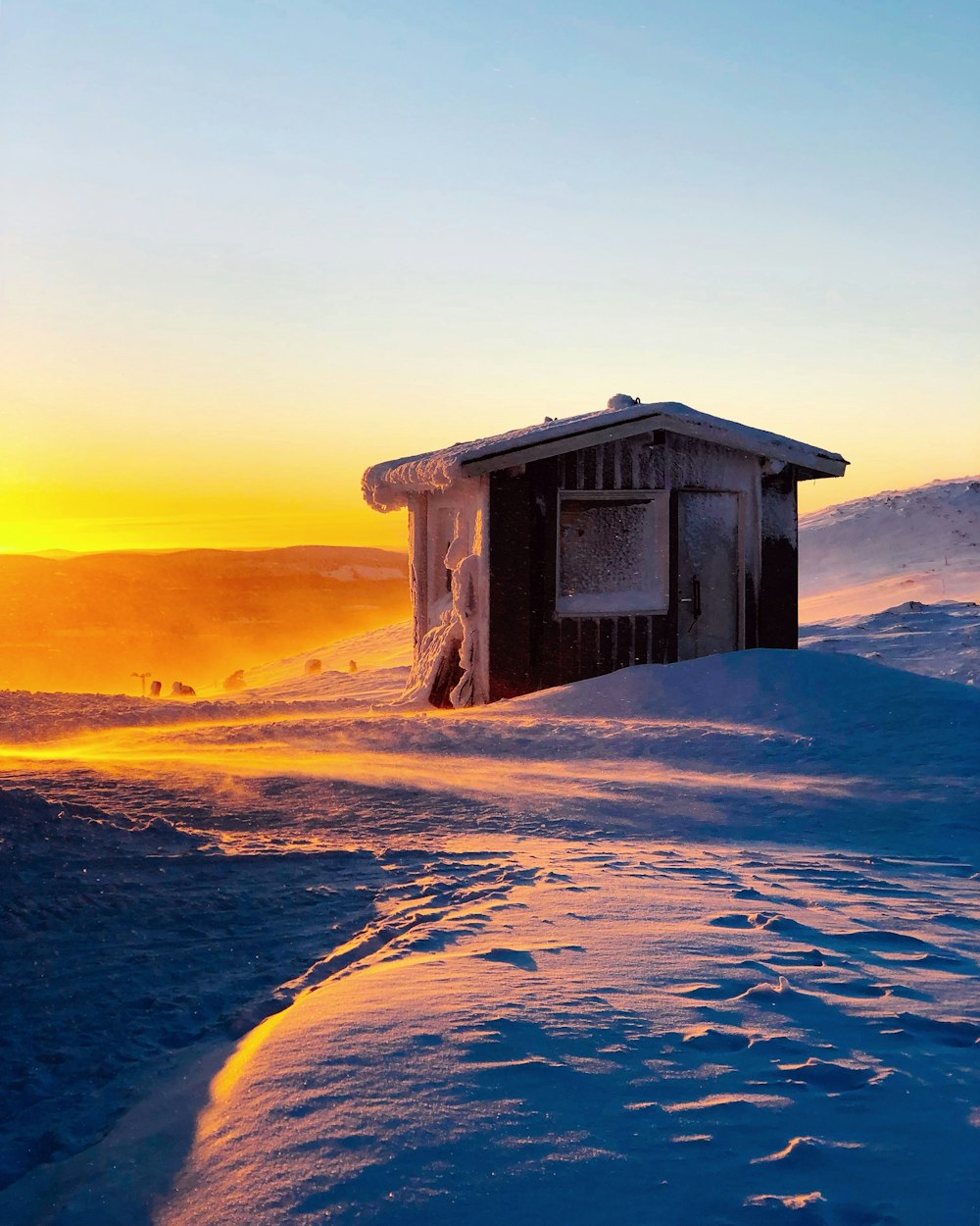 brown wooden house on white snow covered ground during sunset