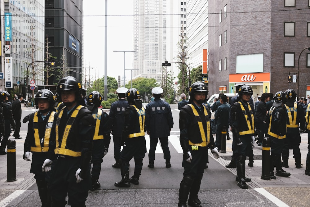 group of men in blue and yellow jacket standing on sidewalk during daytime