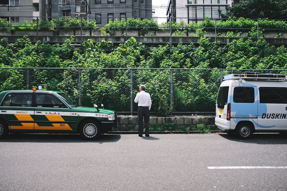 man in white shirt standing beside green and white car during daytime