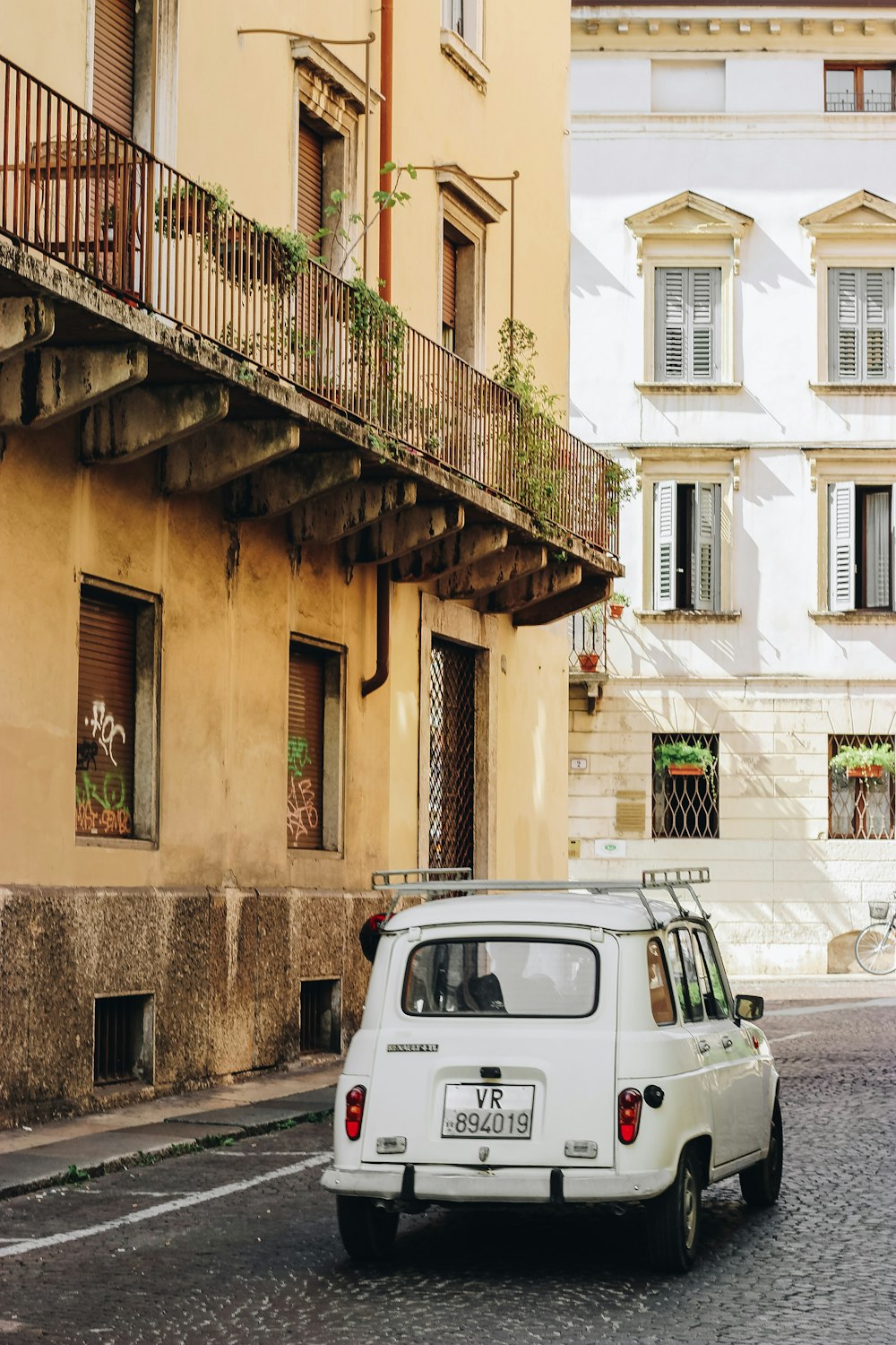 white car parked beside brown concrete building during daytime