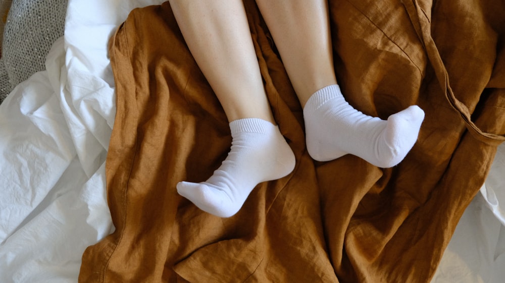 personne en chaussettes blanches sur textile marron