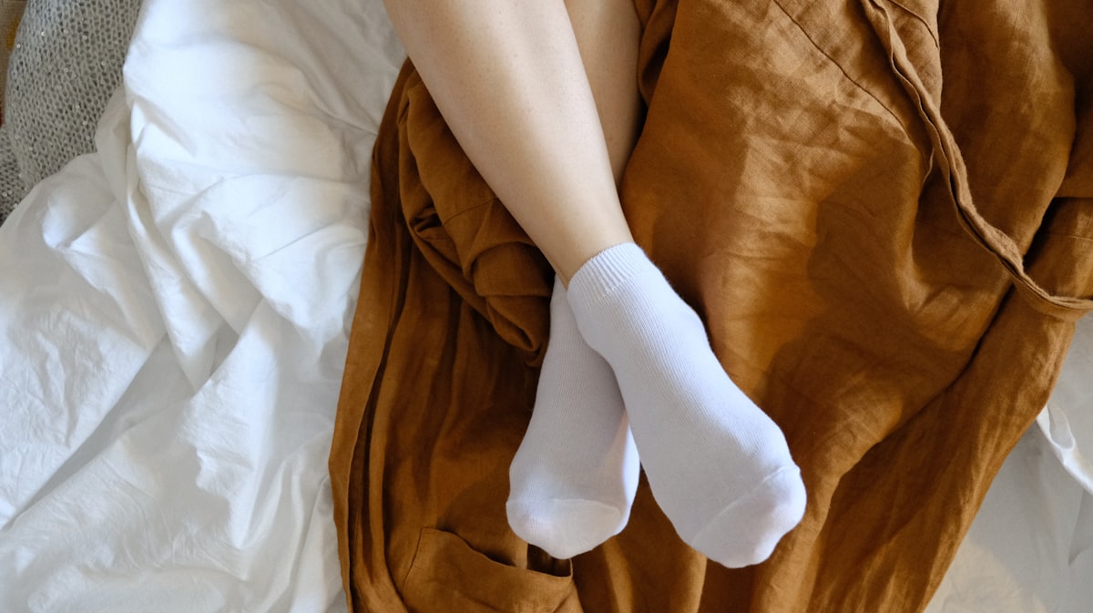 침대에 누워 흰 양말을 신고 있는 두 발