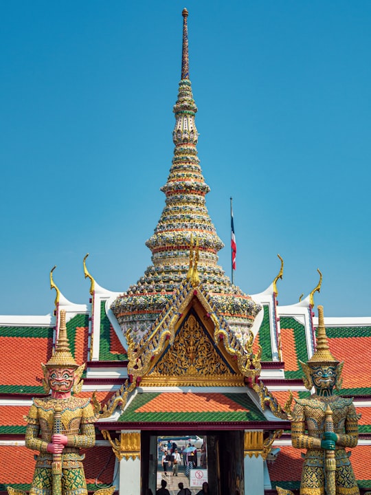 red and gold temple under blue sky during daytime in Wat Phra Kaew Thailand