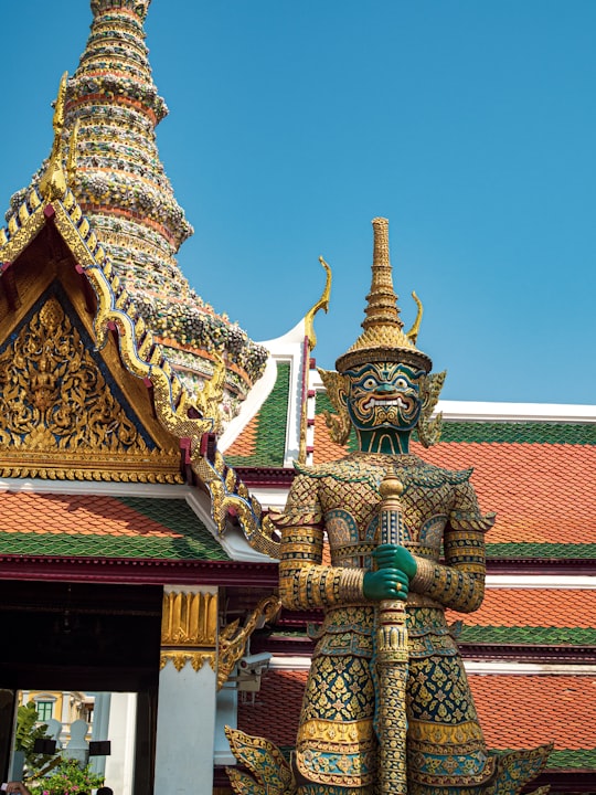 green and gold concrete temple under blue sky during daytime in Temple of the Emerald Buddha Thailand