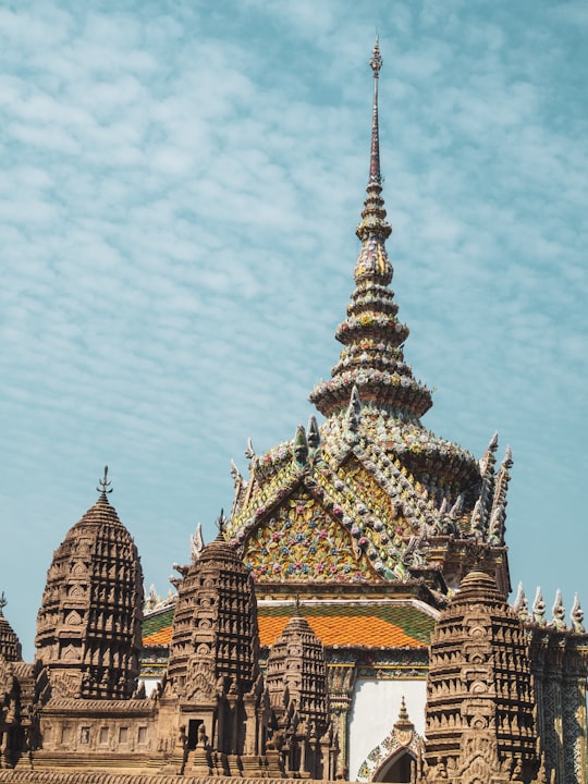 brown and beige concrete building under white clouds during daytime in Grand Palace Thailand