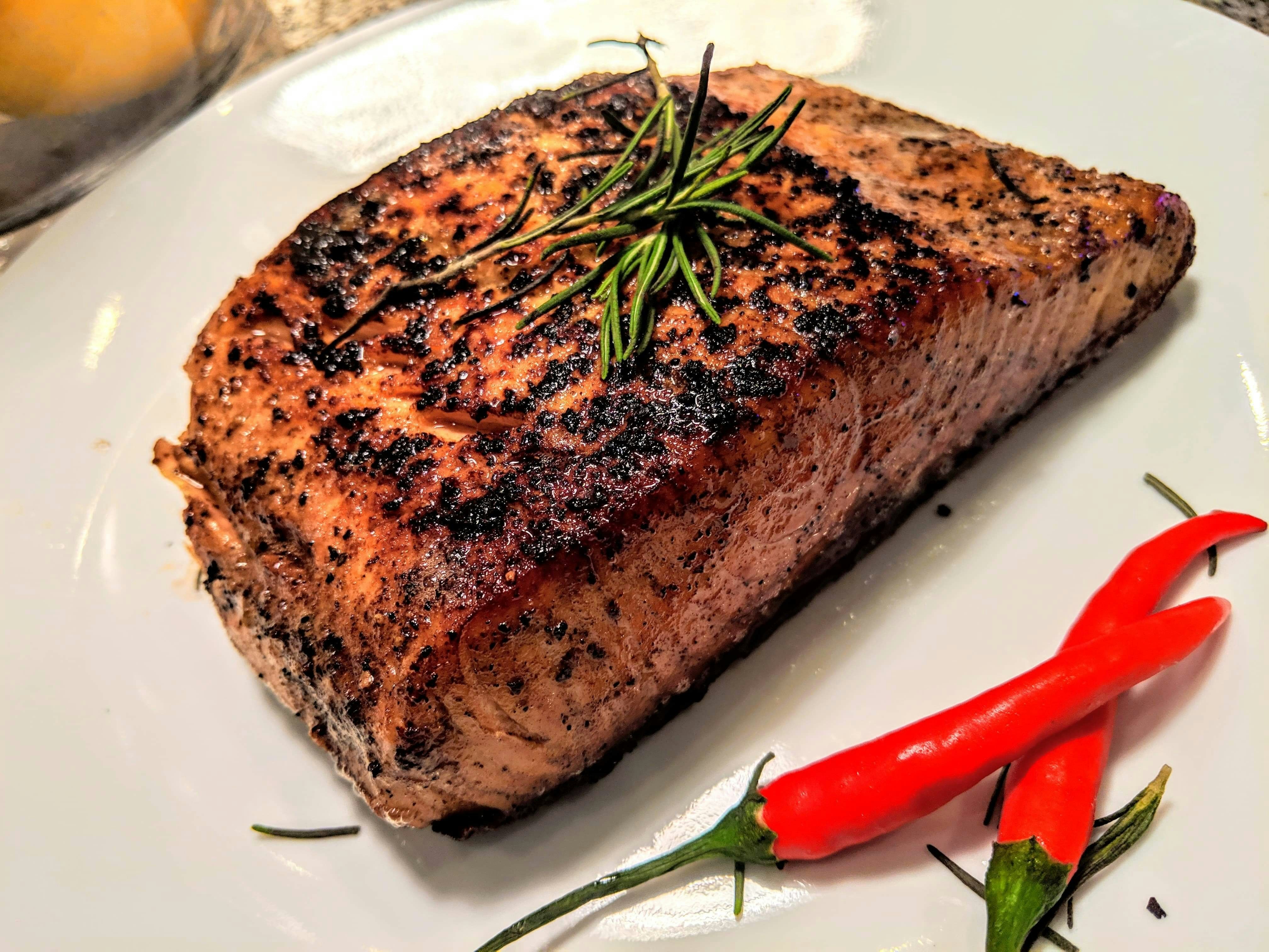 Perfectly grilled salmon fillet with herbs on white plate, bright clean photography