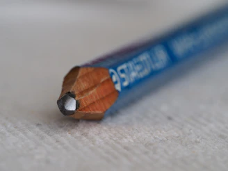 Close-up of a sleek graphite pencil resting on a clean wooden desk.