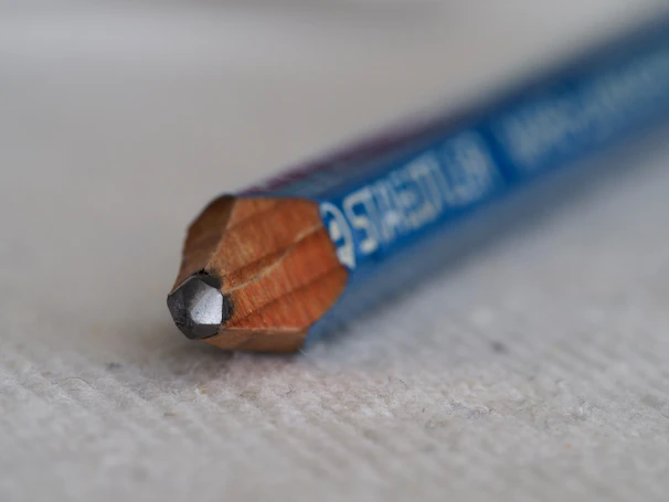 Close-up of a sleek graphite pencil resting on a clean wooden desk.