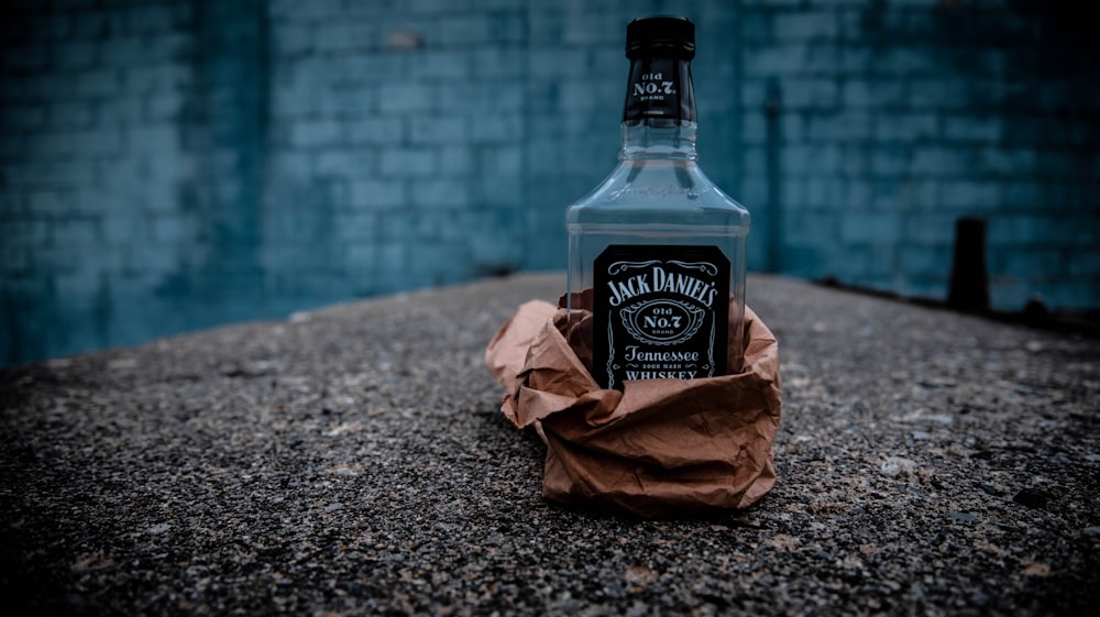 jack daniels old no 7 tennessee honey bottle beside brown paper bag on gray marble