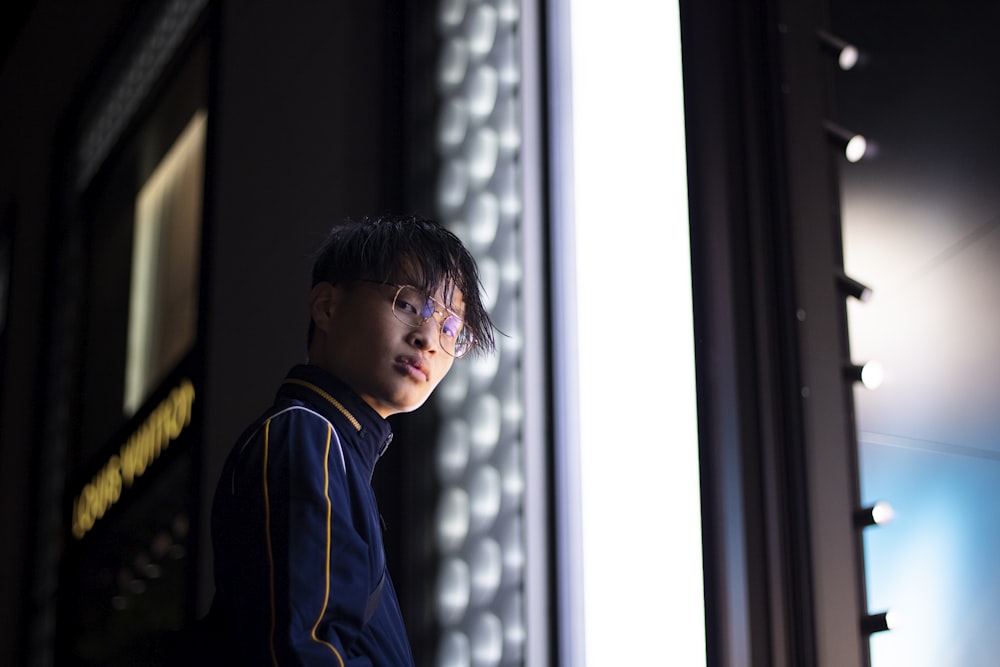Junge in blau-gelbem Kapuzenpulli schaut aus dem Fenster