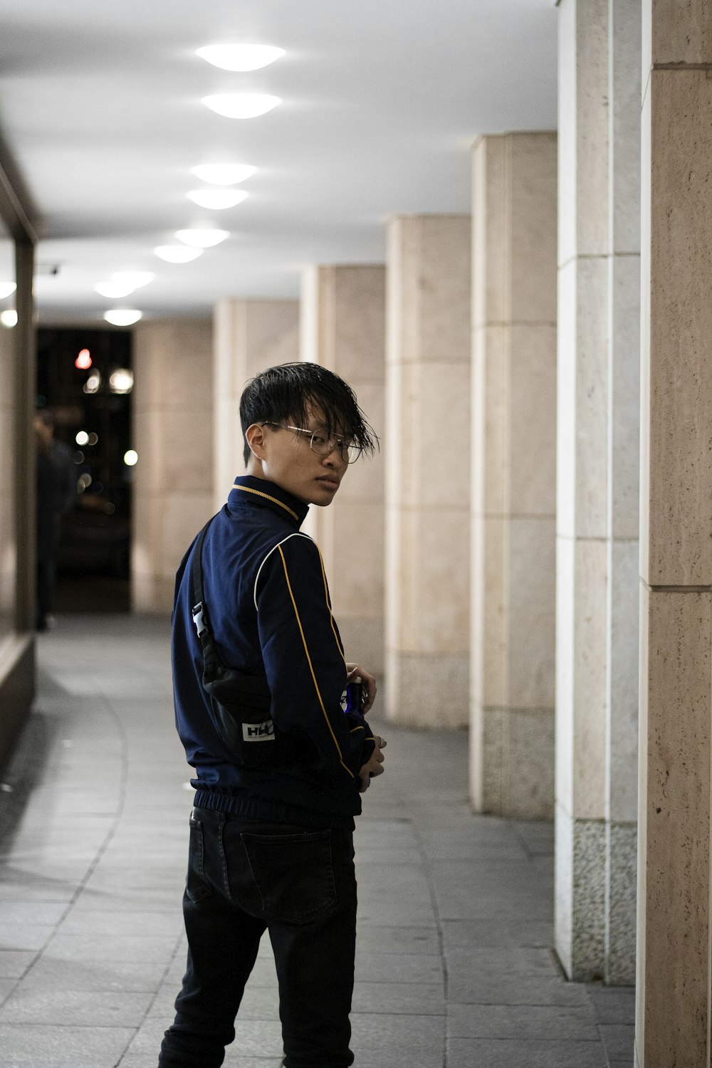 man in blue and white jacket standing beside white concrete wall during daytime