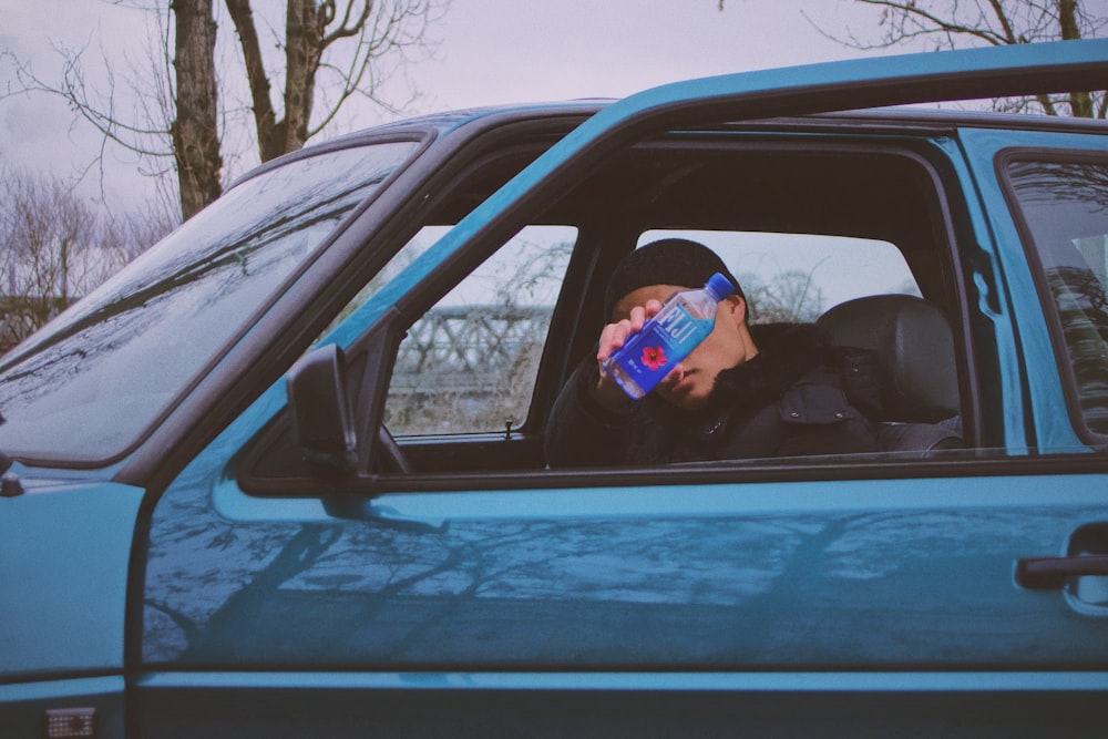 man in black jacket holding blue can