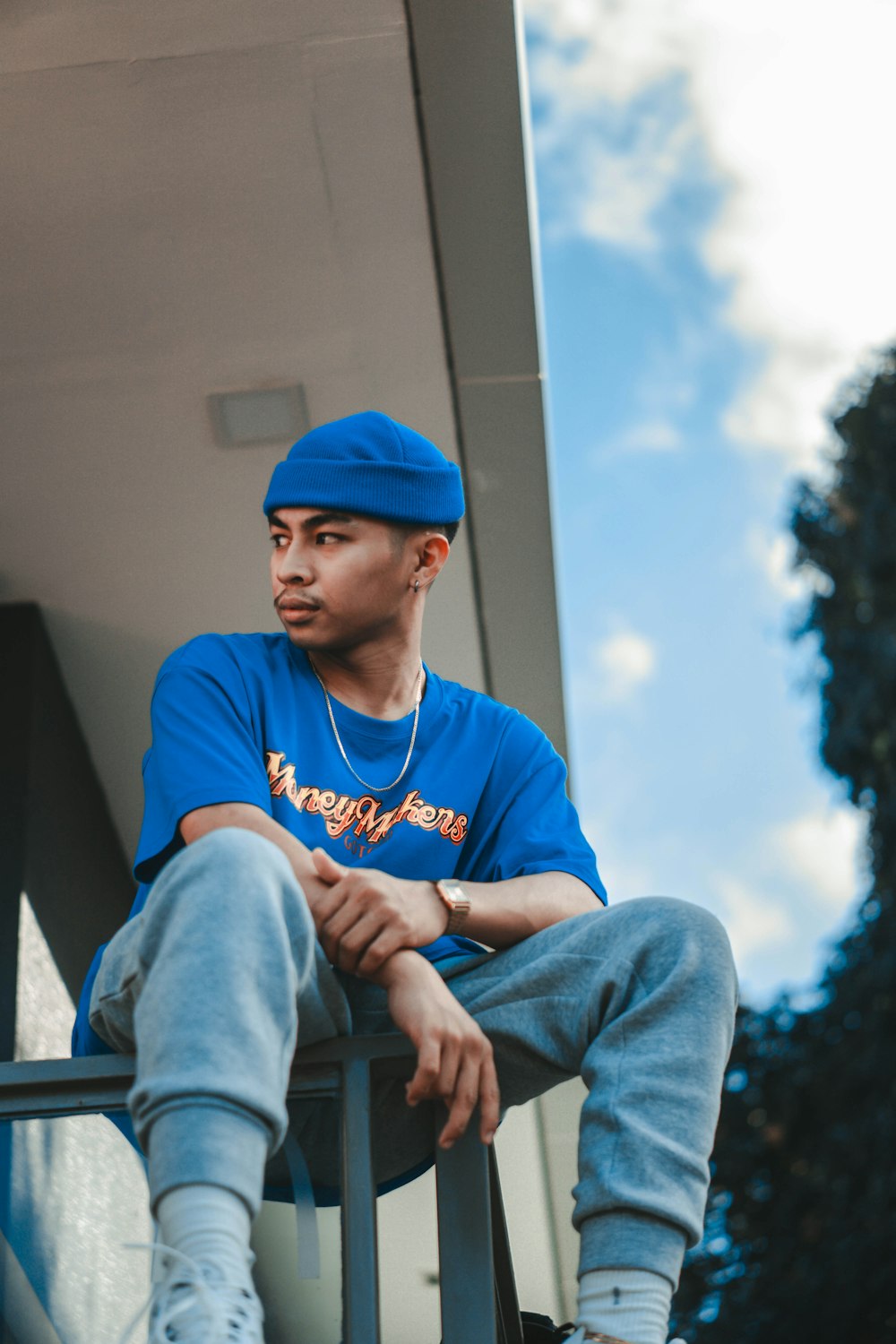 man in blue and white crew neck t-shirt and blue denim jeans sitting on gray