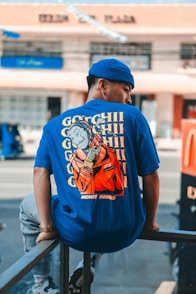 man in blue and white crew neck t-shirt and blue fitted cap standing on sidewalk
