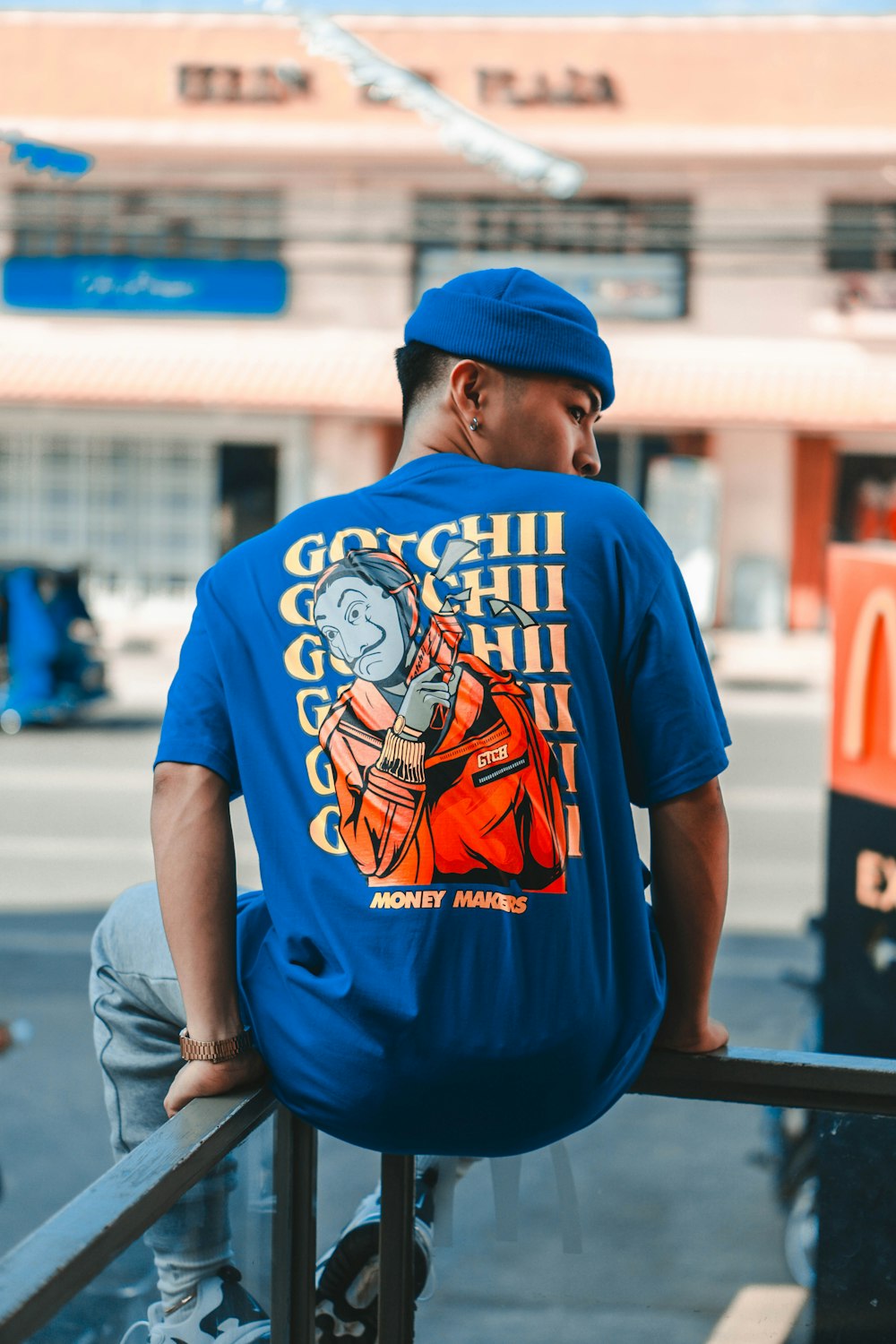 man in blue and white crew neck t-shirt and blue fitted cap standing on sidewalk