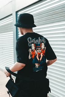 man in black and white crew neck t-shirt wearing black hat sitting on black chair