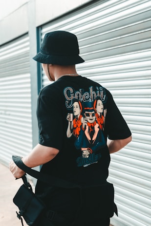 man in black and white crew neck t-shirt wearing black hat sitting on black chair