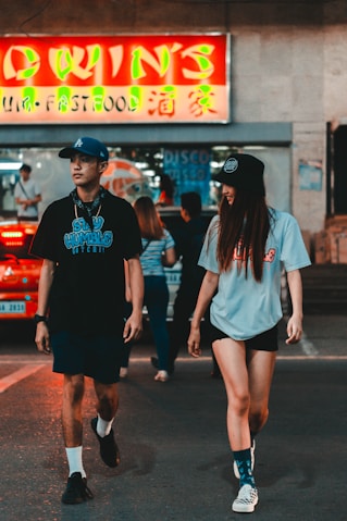 woman in black and white crew neck t-shirt and black shorts standing on sidewalk during