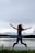 Photograph of a joyful traveler standing by Dal Lake in Kashmir, mist rising over the water.