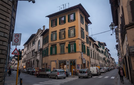 cars parked in front of brown concrete building during daytime in Bologna Italy